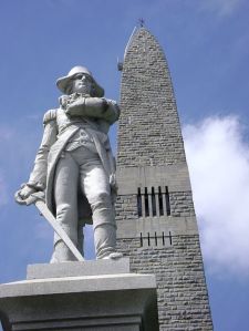 That's a statue of Vermont military leader Seth Warner erected in front of the Bennington obelisk (Credit: Wikipedia)